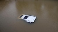 Sebuah mobil yang terendam banjir hanya terlihat atapnya saja.