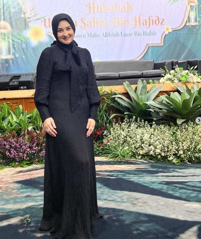 Dalam foto terbarunya, Mona Ratuliu memgenakan setelan dress hitam dengan lengan puff yang dilengkapi jilbab warna senada. Pilihan gaya hijab yang polos dan konvensional membuatnya terlihat elegan. Foto: Instagram @monaratuliu