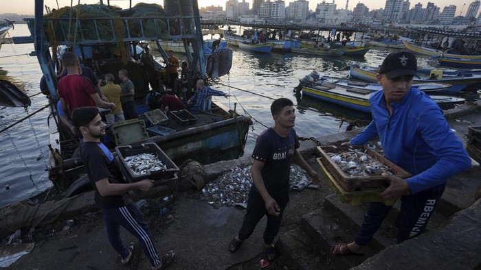 Palestinian fishermen pull fishing nets into their trawlers at the seaport in Gaza City, Thursday, Sept. 7, 2023. After allegedly uncovering explosives hidden in clothing shipped from Gaza to the West Bank, the Israeli government opted for a punitive response this week, clamping down on all cargo shipments out of Gaza and choking off the territory's already ailing economy. (AP Photo/Adel Hana)