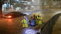 Para petugas penyelamat bergerak menyelamatkan para pengendara yang terjebak di dalam kendaraan mereka yang ada di tengah genangan banjir.   