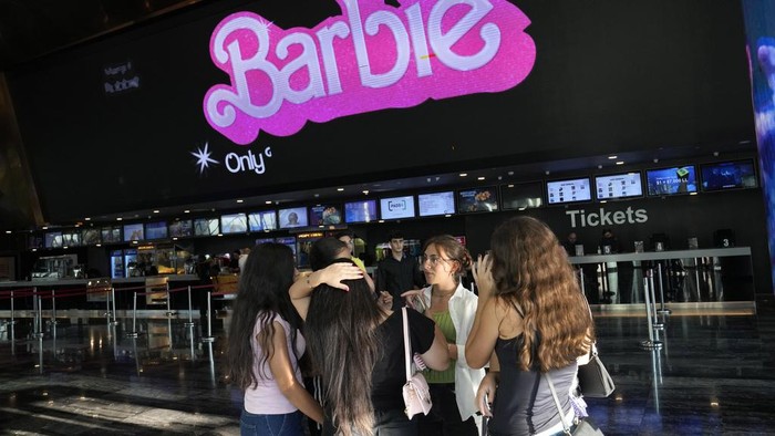 Sempat Dilarang, Film Barbie Akhirnya Tayang Perdana di Lebanon A man takes pictures of his daughters who show their tickets in front of a display panel showing the movie
