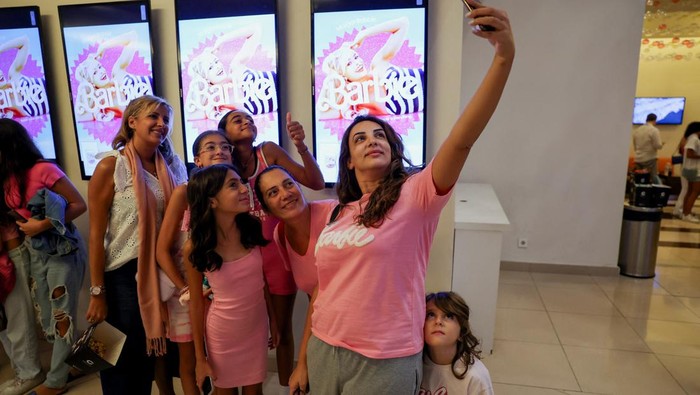 Mira Rammouz and her family take a selfie in front of displays showing the 'Barbie' movie title on the first day of the screening of the movie in Beirut, Lebanon September 7, 2023. REUTERS/Emilie Madi