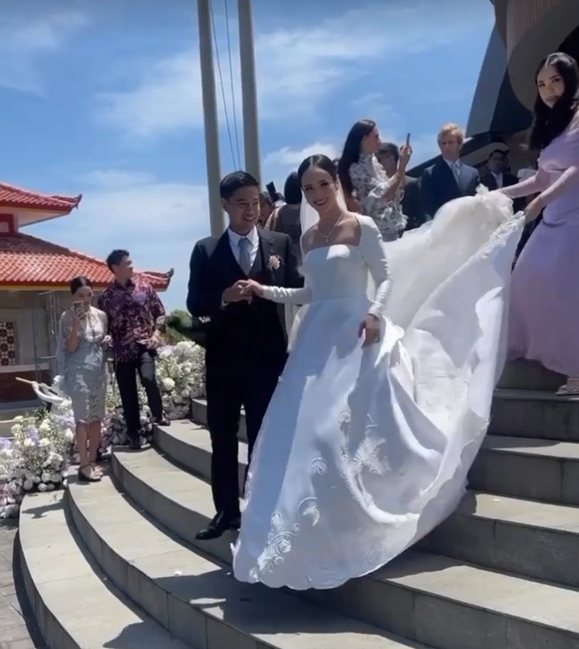 Gaun dari koleksi Monica Ivena ini minim detail namun tetap terlihat megah berkat hiasan bordir serta ekor panjang dan lebar. Foto: Instagram/@pammybowie