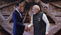 Presiden Jokowi, yang mengenakan setelan jas berwarna biru tua, disambut oleh Perdana Menteri (PM) Narendra Modi. Kedua pemimpin negara pun tampak berfoto bersama sambil berjabat tangan dengan latar belakang roda yang menjadi ikon Kornark Sun Temple, yang merupakan bagian dari situs warisan dunia UNESCO. (AP Photo/Evan Vucci)