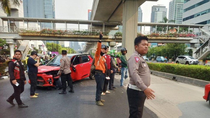 Satu unit mobil berwarna merah mengalami kecelakaan di Jalan HR Rasuna Said, Setiabudi, Jaksel. Mobil itu mengalami kerusakan pada bodi depan akibat kecelakaan. (IG TMC Polda Metro Jaya)