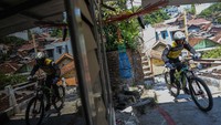 Pebalap sepeda melaju saat berusaha melewati lintasan di gang sempit dalam kejuaraan Gajahmungkur Ultimate Urban Downhill 2023 di Bendungan, Semarang, Jawa Tengah, Minggu (10/9/2023).  
