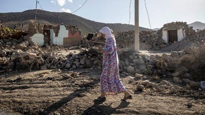A woman walks past destroyed houses after an earthquake in the mountain village of Tafeghaghte, southwest of the city of Marrakesh, on September 9, 2023. Moroccos deadliest earthquake in decades has killed more than 1,300 people, authorities said on September 9, as troops and emergency services scrambled to reach remote mountain villages where casualties are still feared trapped. (Photo by FADEL SENNA / AFP)
