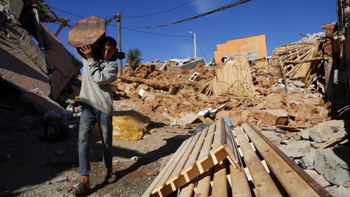 A person carries an item of furniture, in the aftermath of a deadly earthquake, in a hamlet on the outskirts of Talaat NYaaqoub, Morocco, September 11, 2023. REUTERS/Hannah McKay