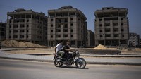 Warga Palestina yang mengendarai sepeda motor di depan proyek perumahan yang didanai Mesir di Jalur Gaza utara, Minggu (27/8/2023). (AP Photo/Fatima Shbair)  