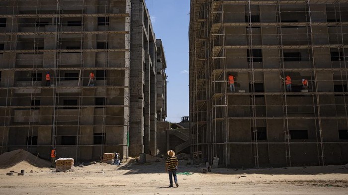 Palestinians on a motorcycle pass nearly completed Egyptian-funded residential buildings in northern Gaza Strip, Sunday, Aug. 27, 2023. Scores of displayed Palestinian families are awaiting completion of nearly 1,400 homes, but the project has become mired in political disputes between the Palestinian Authority and Gaza’s Hamas-run government.(AP Photo/Fatima Shbair)