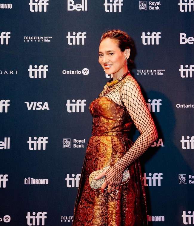 Ine Febriyanti mengenakan gaun dengan aksen jaring-jaring pada bagian dada hingga lengan. Gaun berpotongan A-line itu terbuat dari tenun berwarna emas. Foto: Instagram