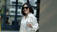 Gaya kecenya tak pernah ketinggalan bahkan saat memesan kopi dari kafe. Kemeja putih bergaya formal menjadi outfit untuk bepergian. Foto: Instagram/kikiamaliaworld