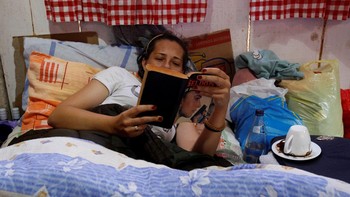 Tidak semua orang rupanya rebahan sambil main gadget. Ada juga yang bergaya lama, rebahan sambil baca buku. Foto: REUTERS/Stevo Vasiljevic