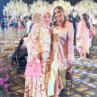 Millen tampil mengenakan dress panjang berwarna hijau tosca dipadukan dengan outer bernuansa merah muda dan ungu. Rambut panjangnya tampak simpel dengan hanya diikat satu ke belakang. Foto: Instagram/@millencyrus