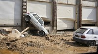 Dalam foto yang disediakan oleh pemerintah Libya ini, sebuah mobil tergeletak di depan toko setelah terbawa air banjir di Derna, Libya, pada Senin (11/9/2023). Libyan Government via AP  