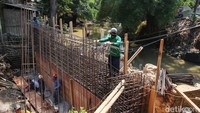 Pekerja menyelesaikan pembuatan rangka untuk tiang jembatan.  