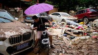 Lumpur menutupi jalan-jalan dan mobil, sampah berserakan di seluruh penjuru seusai banjir menggenangi kota.  