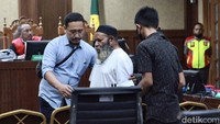 Lukas Enembe dipapah menuju kursi pesakitan.  