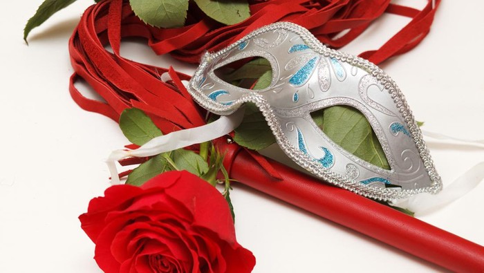 Red whip, rose and mask on a white