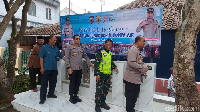 Polisi berfoto di instalasi air bersih bantuan untuk masyarakat.