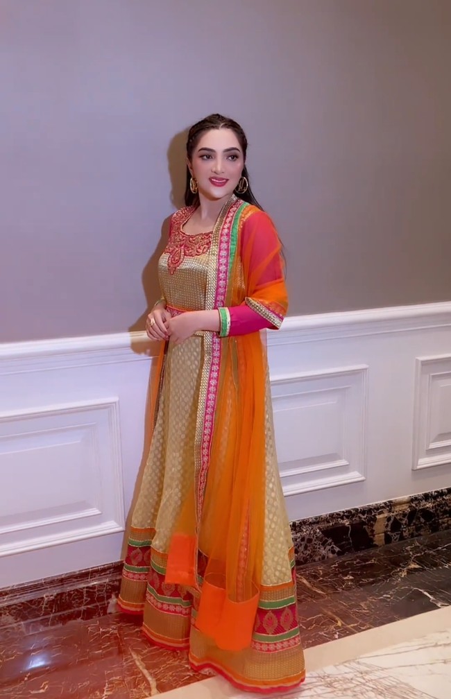 Ashanty tampil dengan busana cerah memadukan gaun warna emas-pink serta outer oranye. Tak lupa sepasang anting hoop melengkapi gayanya. Foto: Instagram