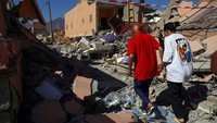 Imane Ait Said, seorang siswa berusia 19 tahun yang kehilangan 10 kerabatnya akibat gempa, berjalan bersama ayah Ibrahim menuju rumah mereka yang rusak akibat gempa mematikan, di Talat NYaaqoub, Maroko 13 September 2023.  