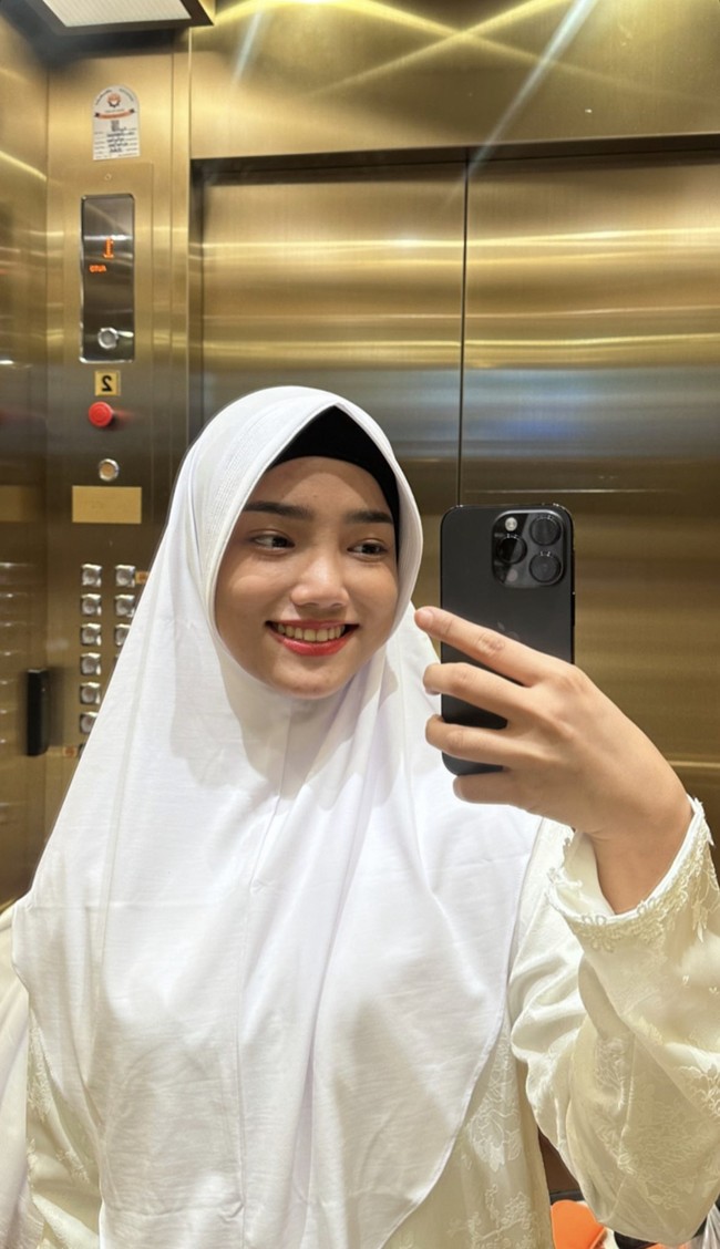 Berada di dalam lift, selebriti internet dan kreator konten ini mengunggah mirror selfie. Dia mengenakan hijab bergo warna putih dilengkapi dengan inner hijab warna hitam. Fuji pun menebar pose senyum. Foto: Dok. Instagram @fuji_an.