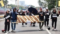 Dalam aksi tersebut, massa buruh membawa keranda yang ditutupi kain dan diberi tulisan “Alm. Munir”.