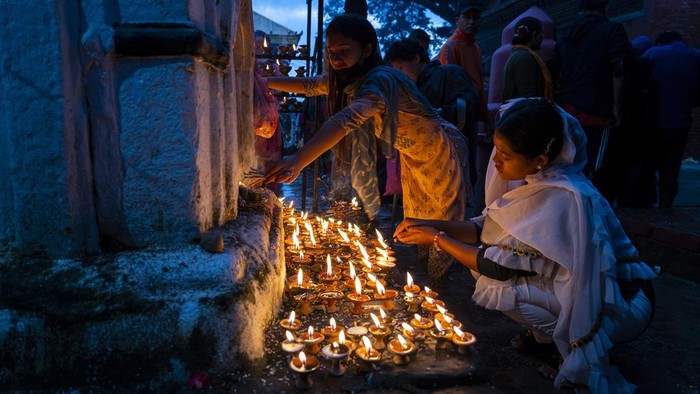 A Nepalese devotee lights an oil lamp during Kuse Aunsi festival at the Gokarneshwor Temple, Kathmandu, Nepal, Thursday, Sept. 14, 2023. Kuse Aunsi is a festival of Nepal where fathers, living or dead, are honored. Children with living fathers show their appreciation by giving presents and sweets and those whose fathers are deceased pay tributes at the Gokarneshwar temple. (AP Photo/Niranjan Shrestha)