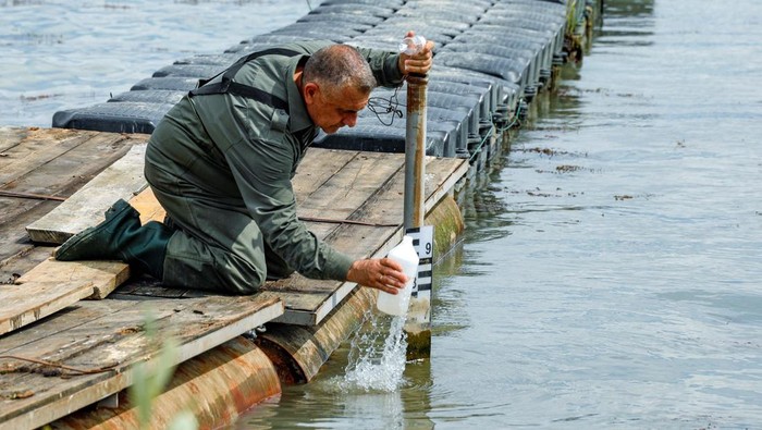 Potret Danau Tertua di Eropa yang Terus Mengering A worker takes water samples in the village of Stenje, North Macedonia September 7, 2023. Water levels at Prespa Lake, located in North Macedonia, Greece and Albania have reached their lowest point in centuries following dry seasons. REUTERS/Ognen Teofilovski