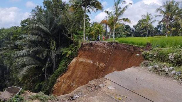 Jalan ambles menimbulkan lubang sangat besar hingga menggerus area persawahan di Tegallalang.