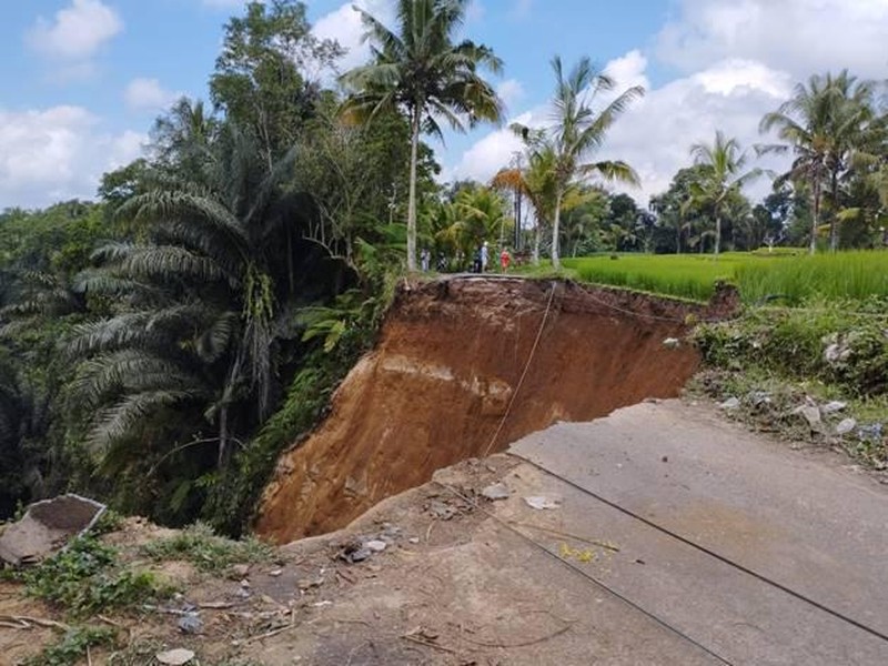 Jalan ambles menimbulkan lubang sangat besar hingga menggerus area persawahan di Tegallalang.