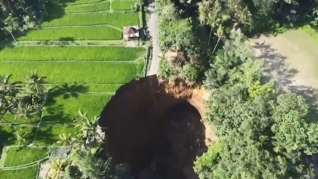 Jalan ambles menimbulkan lubang sangat besar hingga menggerus area persawahan di Tegallalang.
