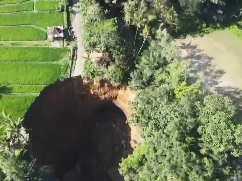 Jalan ambles menimbulkan lubang sangat besar hingga menggerus area persawahan di Tegallalang.