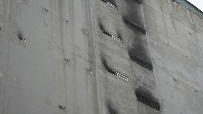 A security officer walks past burned vehicles in an apartment building that was caught fire in Hanoi, Vietnam Thursday, Sept. 14, 2023. A fire broke just before midnight Tuesday in the apartment building that killed scores of people. (AP Photo/Hau Dinh)