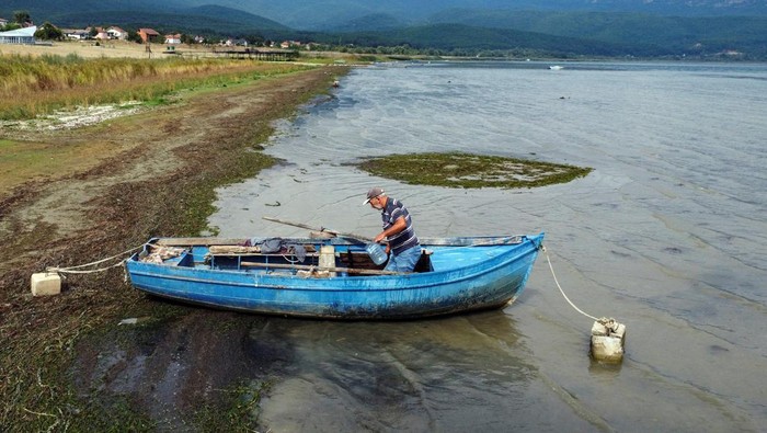 Potret Kekeringan Melanda Danau Tertua di Eropa Fisherman Vane Vasilevski works on his rowing boat at Prespa Lake in the village of Stenje, North Macedonia September 7, 2023. Water levels at Prespa Lake, located in North Macedonia, Greece and Albania have reached their lowest point in centuries following dry seasons. REUTERS/Ognen Teofilovski