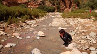 Seorang anak membilas wajahnya dengan air sungai di Amizmiz, Maroko, Kamis (14/9/2023). (REUTERS/Nacho Doce)