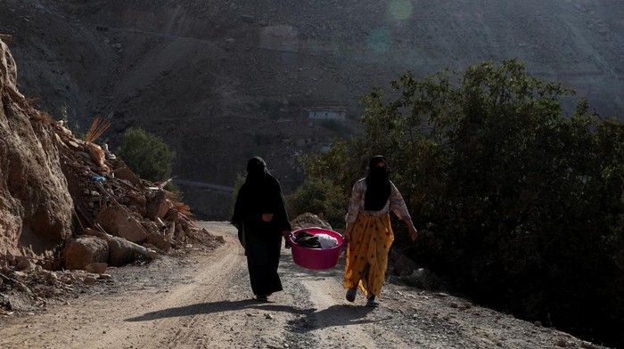 People carry water and belongings through the village in the aftermath of a deadly earthquake, in Anzelfi, Morocco September 14, 2023. REUTERS/Hannah McKay