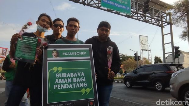 Bonek, suporter Persebaya bagi-bagi bunga untuk pengendara dengan pelat nomor luar Surabaya.