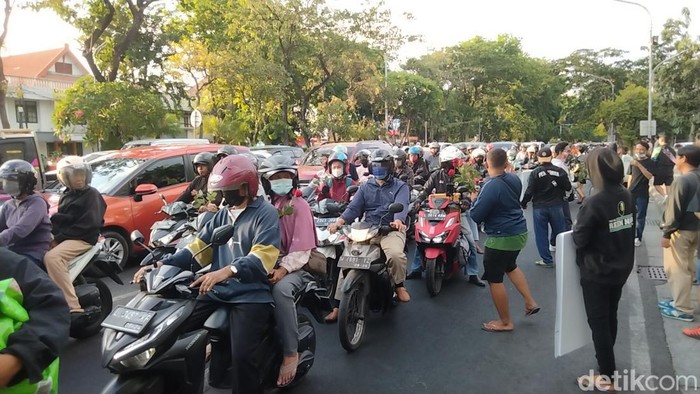 Bonek, suporter Persebaya bagi-bagi bunga untuk pengendara dengan pelat nomor luar Surabaya.