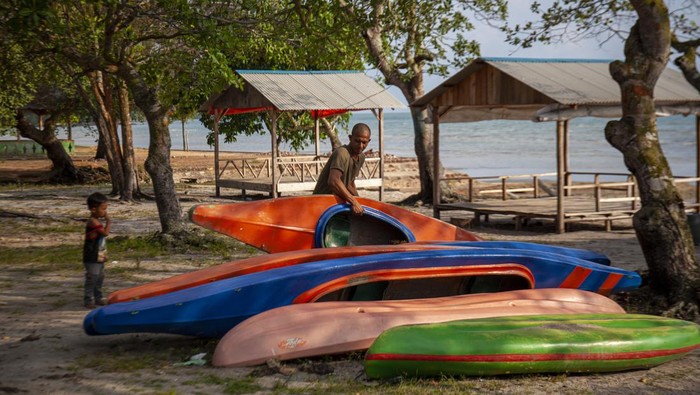 Seorang pengelola persewaan fasilitas wisata menyusun perahu kano di kawasan pariwisata Pantai Melayu, Pulau Rempang, Batam, Kepulauan Riau, Sabtu (16/9/2023).
 Pelaku pariwisata di pulau tersebut mengeluhkan sepinya pengunjung setelah terjadinya bentrokan warga dengan Tim Terpadu pada proses proyek strategis nasional (PSN) Rempang Eco-City Pulau Rempang pada Kamis (7/9/2023). ANTARA FOTO/Teguh Prihatna/Spt.