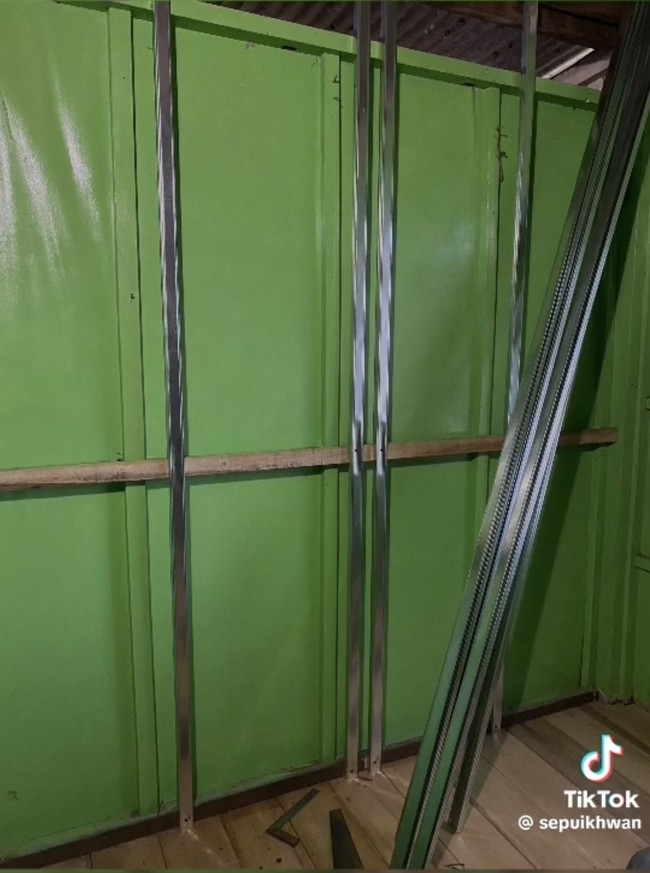 Beberapa tiang-tiang untuk penyangga dinding kamar ditambahkan. Tiang-tiang besi itu tampak diletakkan persis di depan dinding hijau lama kamar tersebut. Foto: TikTok/@sepuikhwan