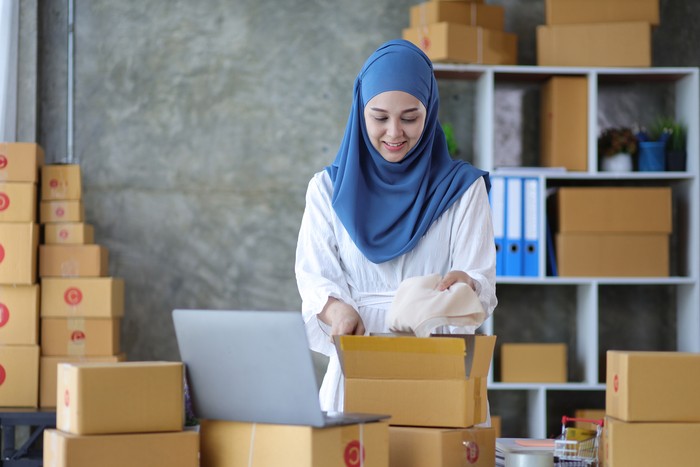 Woman online store small business owner seller entrepreneur packing package post shipping box preparing delivery parcel on table. Ecommerce drop shipping shipment service concept.