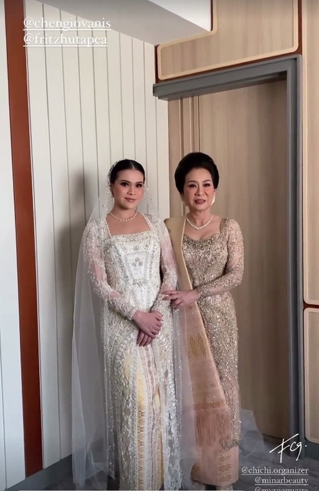 Sementara pengantin wanita, Chen Giovani tampil cantik dalam balutan gaun pengantin putih panjang bertabur payet. Kebayanya itu dipadukan dengan ulos. Dilengkapi dengan veil di kepala dan kalung mutiara yang melingkar di lehernya, penampilan Chen pun jadi makin terlihat anggun dan elegan. Foto: Instagram