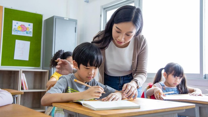 The girl and boy student Take note lecture in the classroom. Young woman teachers give advice on learning to Diversity elementary school children. back to School concept