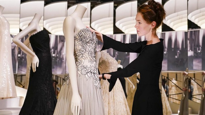 A curator poses next to creations which are displayed as part of the 