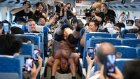 Minoru Suzuki dan Sanshiro Takagi, keduanya pegulat profesional, berkelahi di gang dengan chokehold dan tubuh terbalik, sementara penumpang yang gembira bersorak dan merekam video ponsel.  