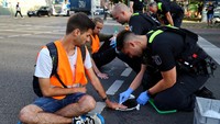 Polisi berusaha melepas lem yang melekatkan tangan demonstran ke aspal jalan di lampu merah Distrik Friedrichshain, Berlin.  