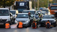 Aktivis iklim dari gerakan Letzte Generation (Generasi Terakhir) memblokir jalan di distrik Friedrichshain untuk memprotes dewan iklim di Berlin, Jerman, Senin (18/9/2023).  