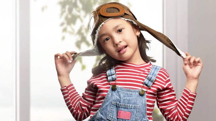Funny asian child with aviator hat and goggles playing at home